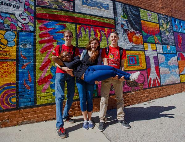 Students pose in front of the mural in Uptown Normal.